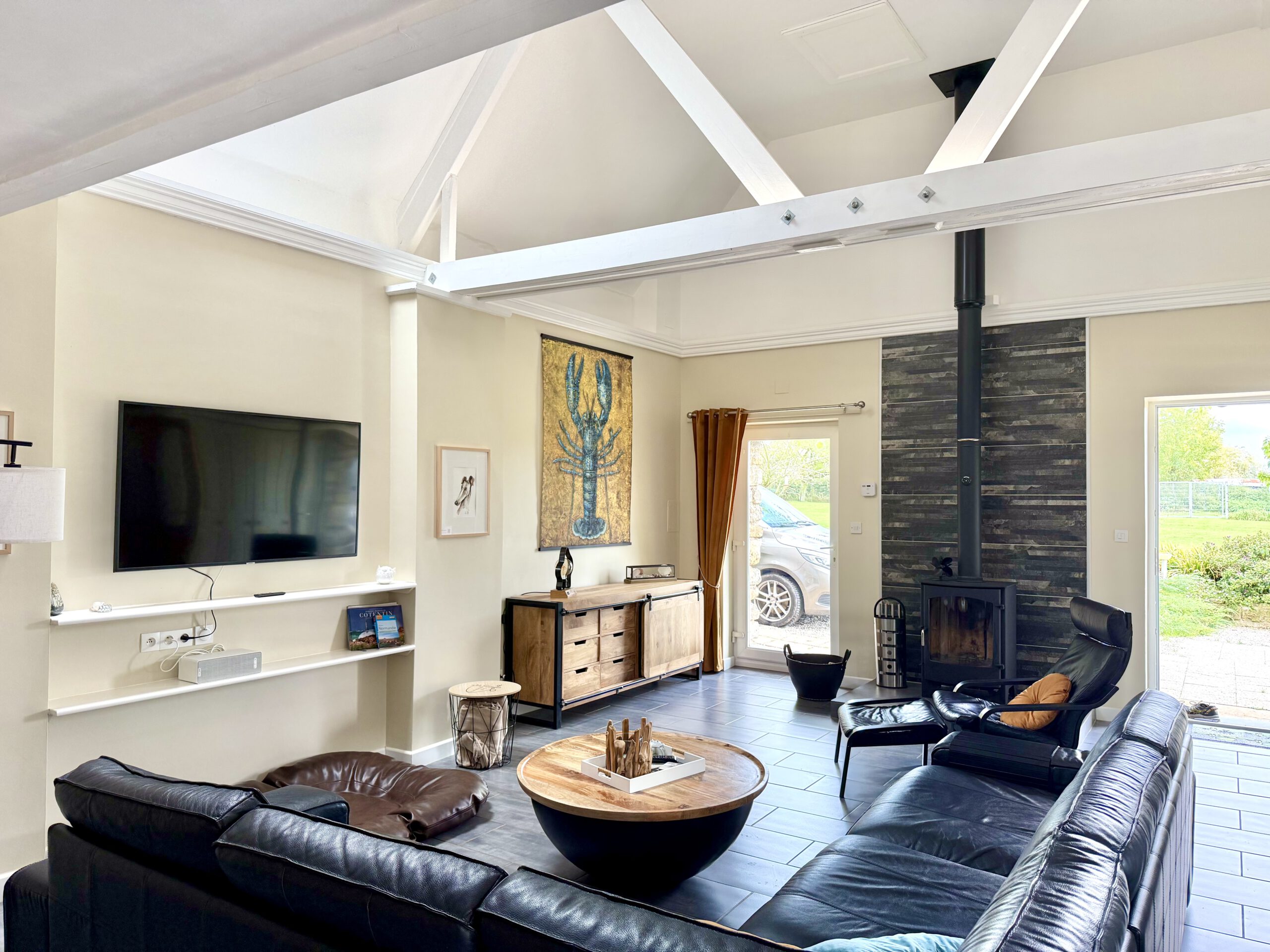 Blick in das Wohnzimmer von Maison Les Grues mit Ledersofa, Kamin, modernen Möbeln, Smart-TV und Sonos Musikbox