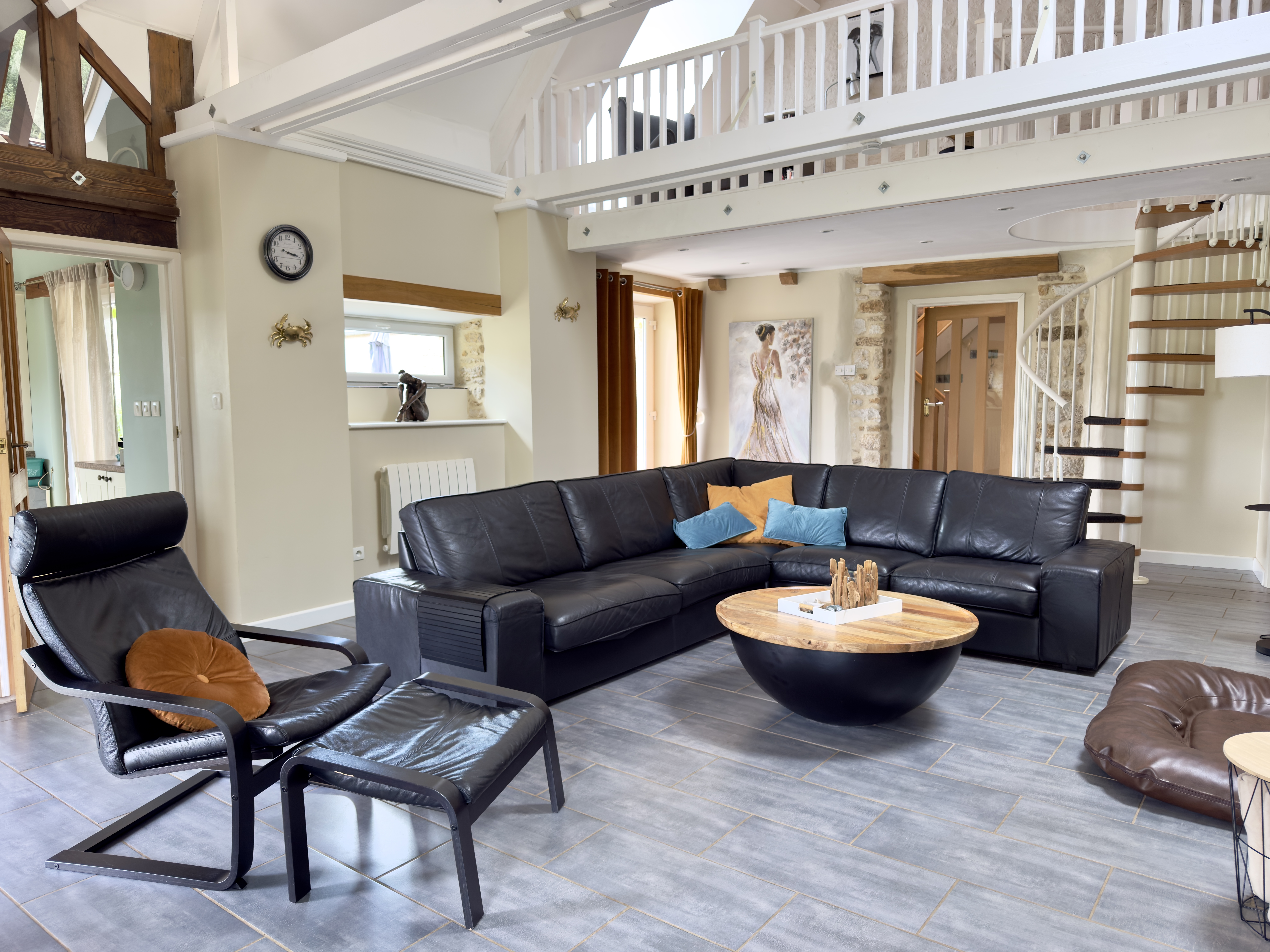 Blick in das Wohnzimmer mit Ledersofa, Ledersessel, Ridgipad, modernen Möbeln und Aufgang zur Galerie