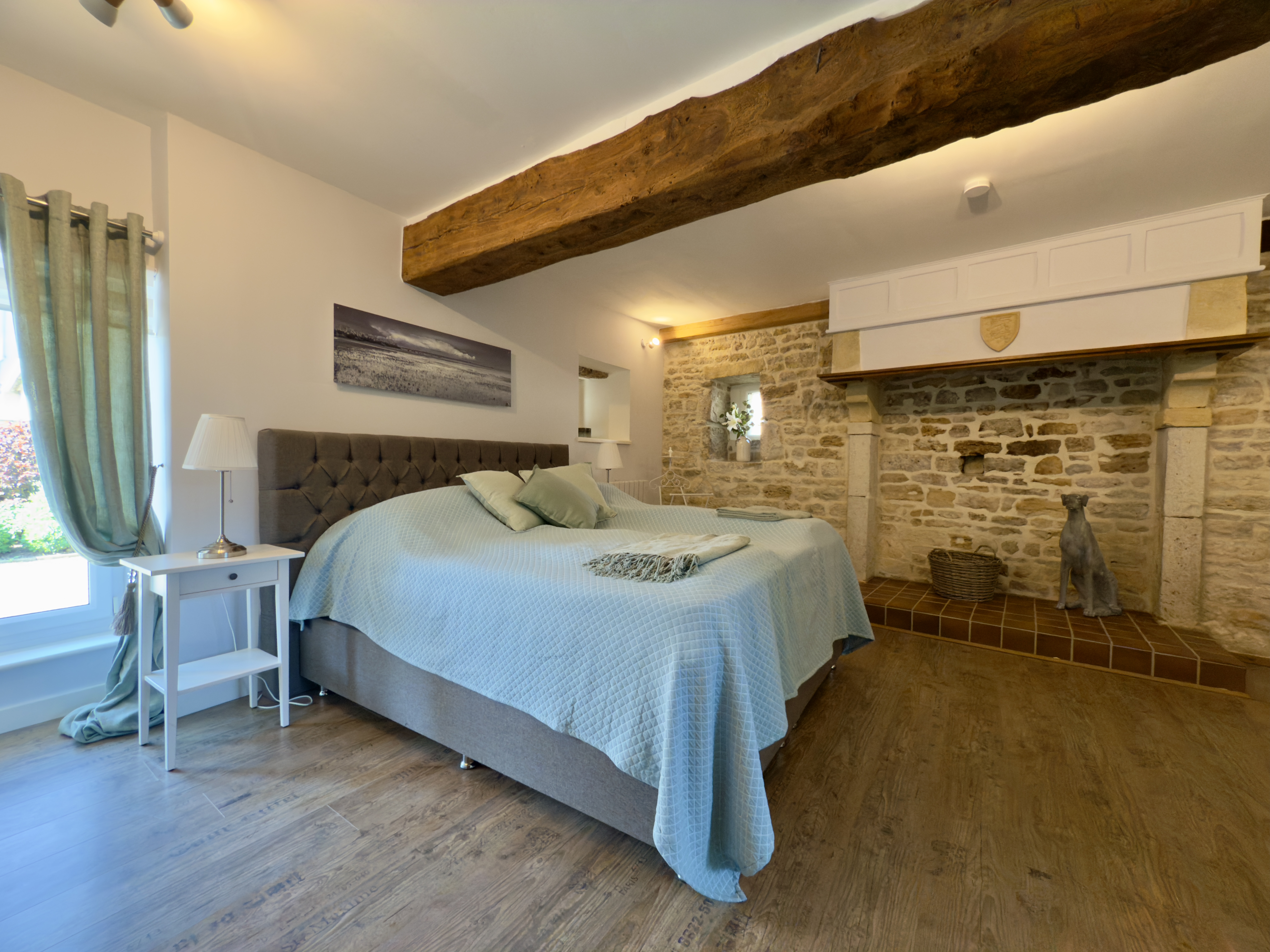 Schlafzimmer im Erdgeschoss von Maison Les Grues mit Boxspringbett, Nachttischen und ansprechender Dekoration